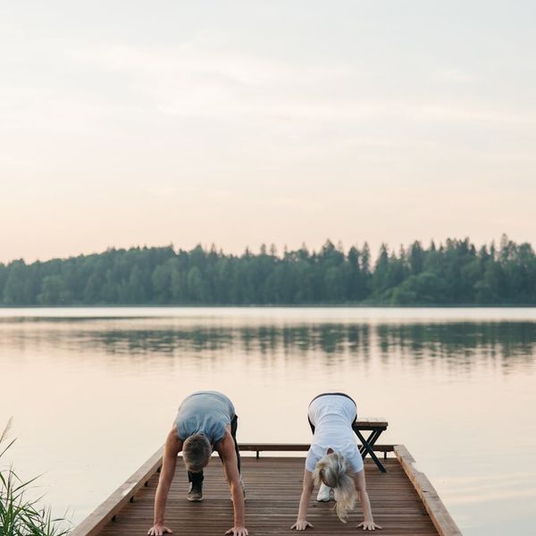 Person stretching peacefully during a sunrise over a calm lake.
